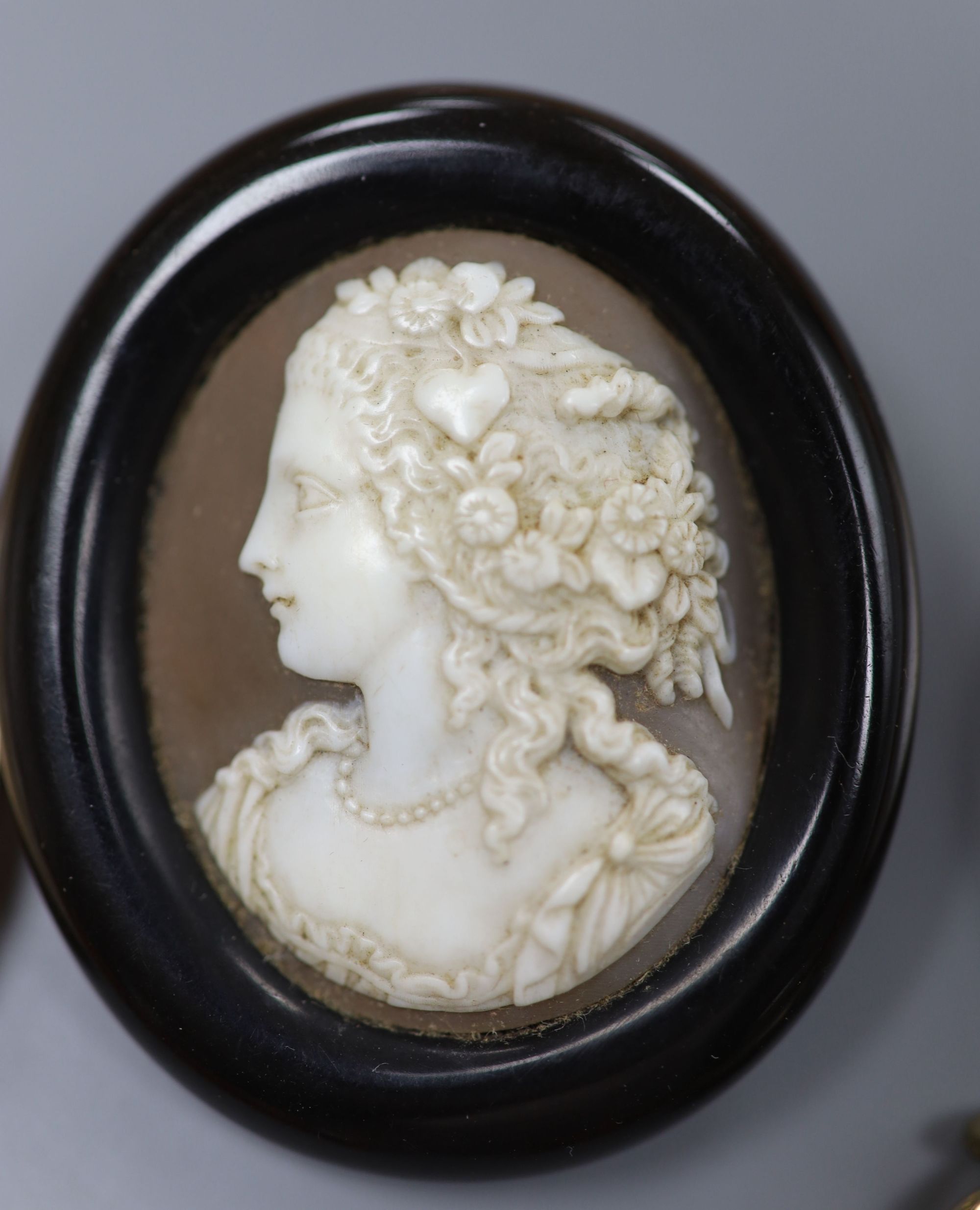 A 9k mounted cameo shell brooch, 46mm, a silhouette pendant, brooch, locket and two amber necklaces.